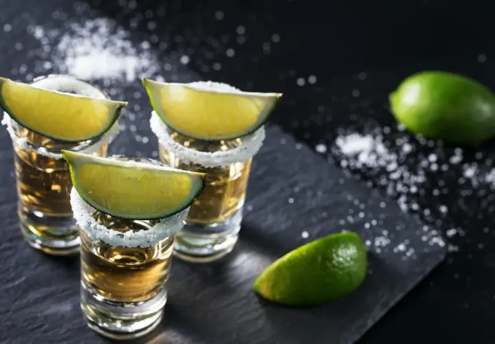 Kieliszki tequili z solą i limonką. Idealne dodatki, by wiedzieć, z czym pić tequilę.