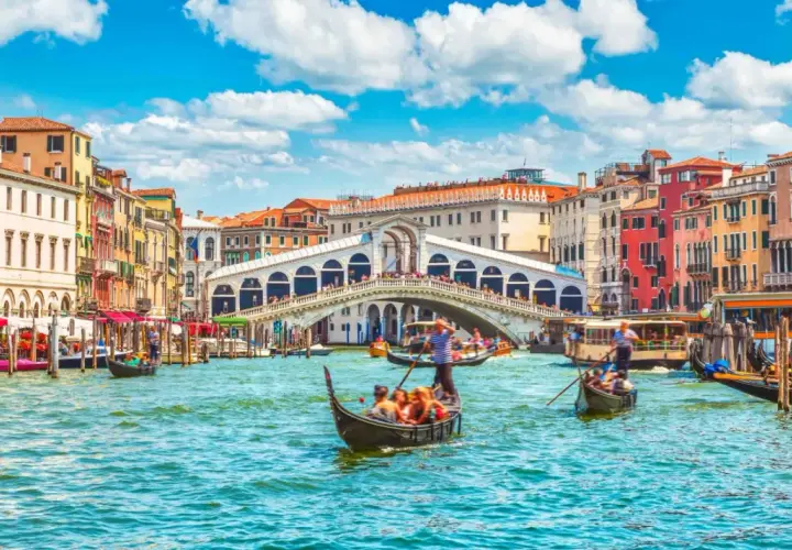 Gondole płynące po Canale Grande w Wenecji, z widokiem na Most Rialto i kolorowe kamienice. Ten region to kwintesencja włoskiego piękna.