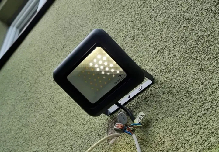 Nowa lampa led żarzy się po włączeniu, oświetlając zieloną ścianę.