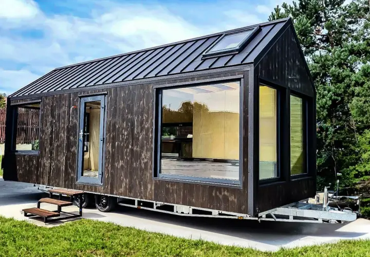 Nowoczesny tiny house w Polsce, z ciemną drewnianą elewacją i dużymi oknami, gotowy na przygodę.