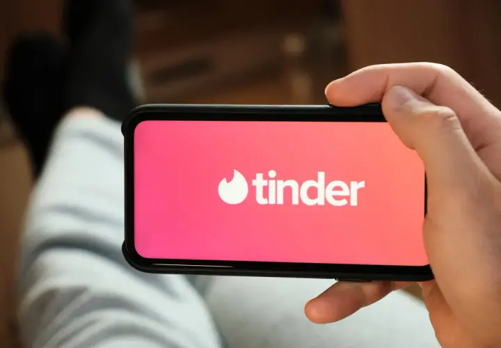 Dłoń trzyma smartfon z logo Tindera. Szukasz alternatywy dla Tindera? Może warto spróbować czegoś nowego.