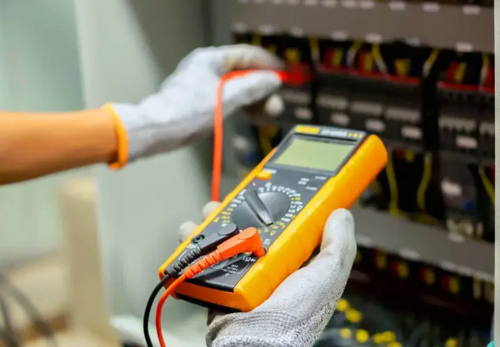 Elektryk z multimetrem wykonuje pomiary elektryczne. Sprawdź nasz cennik usług.