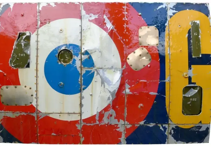 Panneau métallique style pop art, aux couleurs vives et écaillées, rappelant les cocardes d'avions et des chiffres.