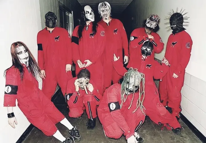 Zespół Slipknot w czerwonych kombinezonach i charakterystycznych maskach, pozuje do zdjęcia w korytarzu.