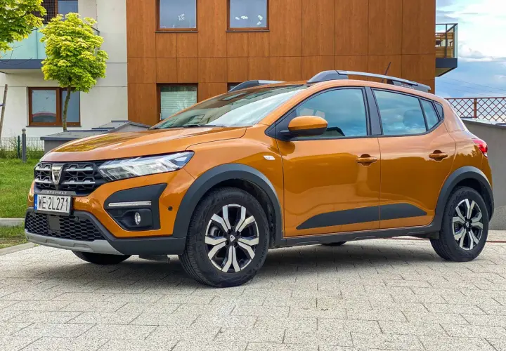 Pomarańczowy Dacia Sandero Stepway na tle nowoczesnego budynku. Zastanawiasz się nad jego spalaniem?