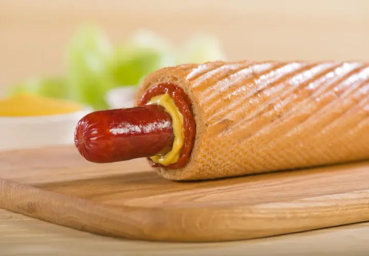 Pyszny hot dog francuski z musztardą i ketchupem na desce.