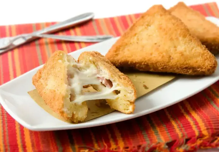 Mozzarella in carrozza in friggitrice ad aria: triangoli dorati e croccanti con cuore filante di mozzarella e prosciutto.