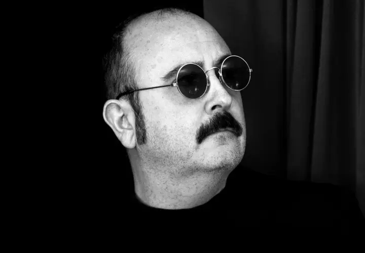 Carlos Areces, con su pareja de gafas redondas y bigote, posa con misterio.