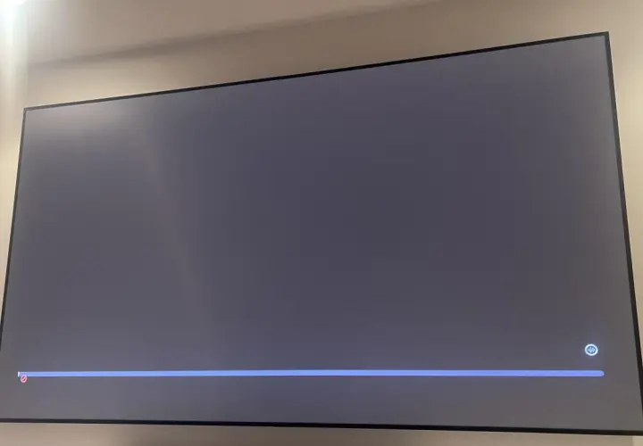 Szary ekran telewizora z niebieskim paskiem postępu i ikoną mikrofonu. Czekam na air play.