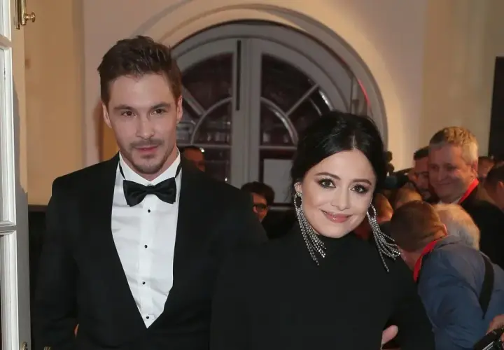 Adriana Kalska z partnerem na czerwonym dywanie, uśmiechnięci i eleganccy.