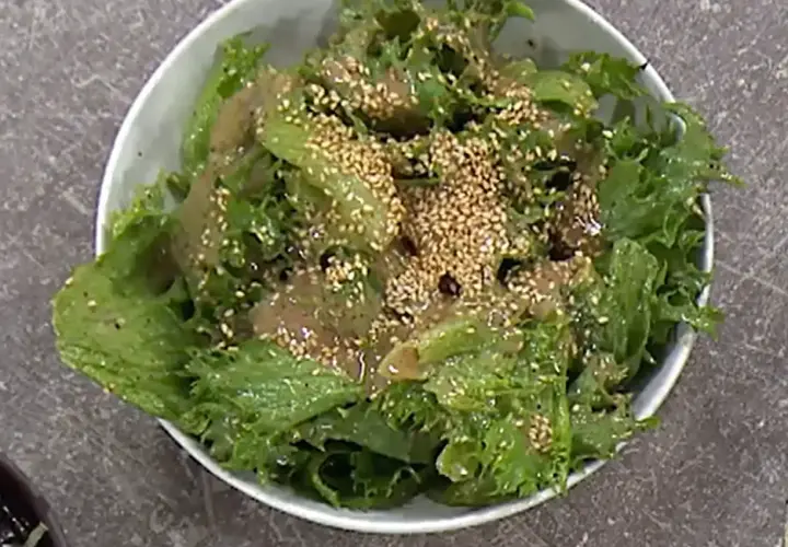 Grön, krispig sallad med sesamfrön och en dressing, perfekt som sallad till paj.