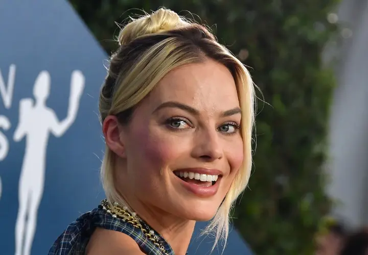 Margot Robbie, l'actrice qui incarne Harley Quinn, rayonne avec un chignon blond et un sourire éclatant.