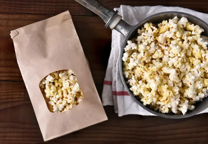 Jak zrobić popcorn w garnku? Świeżo przygotowany popcorn w garnku i papierowej torbie, gotowy do chrupania.
