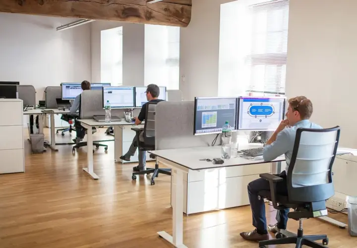 Bureau moderne avec employés travaillant sur des ordinateurs. Un homme utilise un service de bureau cloud pour gérer des données.