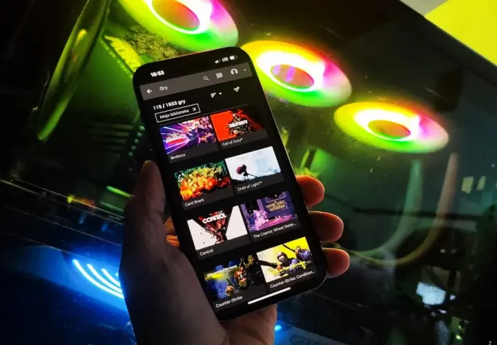 Przeglądanie listy gier na GeForce Now na telefonie, w tle świecące wentylatory komputera.