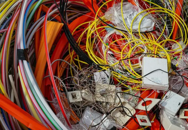 Plątanina kolorowych kabli, przewodów i białych puszek, przypominająca elektrośmieci.