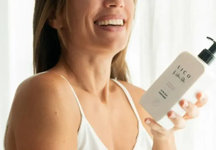 Mujer sonriente sostiene un acondicionador LICO. Descubre para qué sirve el acondicionador del pelo: suavidad y brillo.