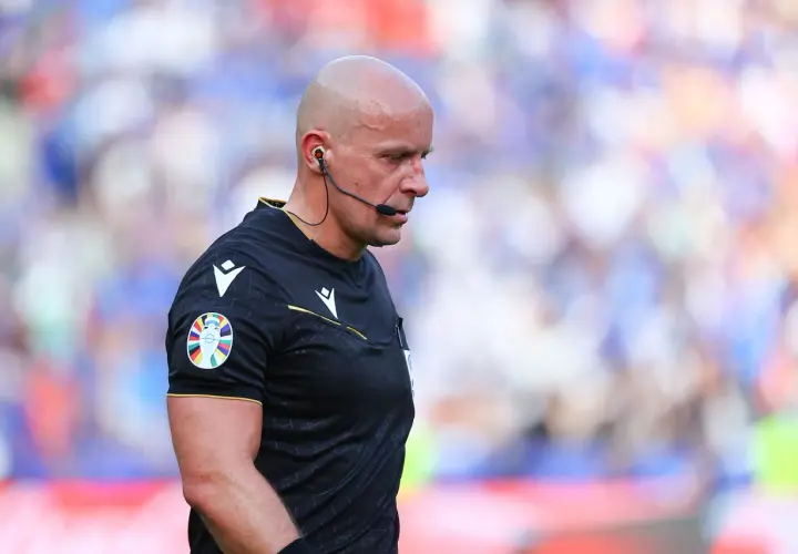 Sędzia Michael Oliver w czarnej koszulce z naszywką Ligi Mistrzów, skupiony na boisku.