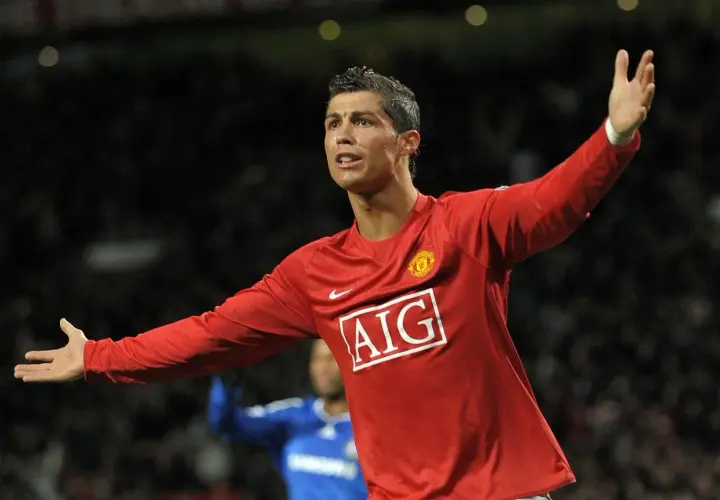 Cristiano Ronaldo w czerwonej koszulce Manchesteru United, z uniesionymi rękami, świętuje bramkę. To był kluczowy moment przed jego transferem.