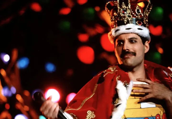Freddie Mercury w koronie i czerwonym płaszczu, śpiewający swoje legendarne piosenki.