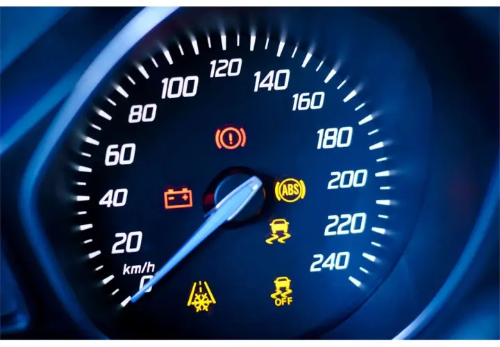Cruscotto auto con tachimetro e spie accese: spia punto esclamativo giallo, ABS, controllo stabilità e batteria.