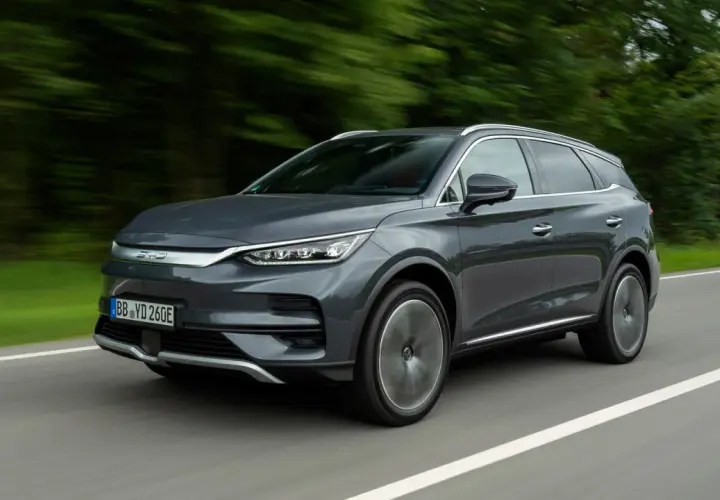 Szary SUV BYD Tang w ruchu drogowym, z rozmytym tłem drzew.