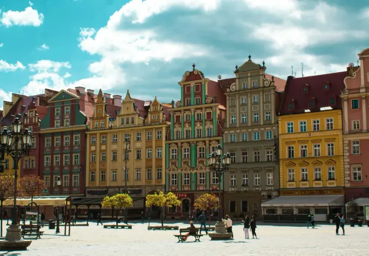 Kolorowe kamienice na wrocławskim Rynku, idealne na city break z Wrocławia. Słoneczny dzień, chmury na niebie.