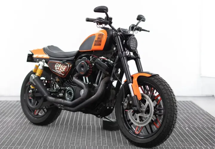 Harley Davidson custom con sella nera, serbatoio arancione e dettagli "Garage". Motore potente e ruote personalizzate.