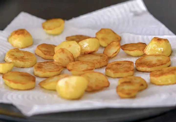 Patatas al horno recién hechas, doradas y crujientes, reposando sobre papel absorbente. ¡Listas para disfrutar!