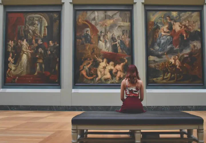 Una donna ammira tre grandi dipinti in un museo, forse provando la sindrome di Stendhal cos'è.