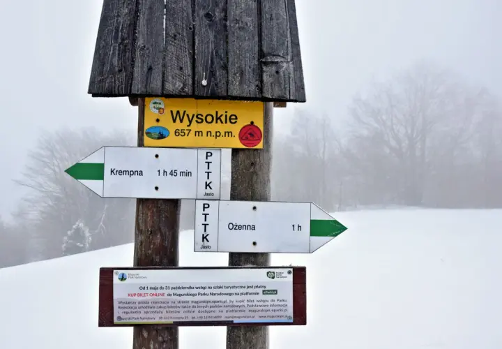 Magurski Park Narodowy atrakcje: drogowskazy szlaków do Krempnej (1h 45min) i Ożennej (1h), szczyt Wysokie (657 m n.p.m.). Informacja o płatnym wstępie.