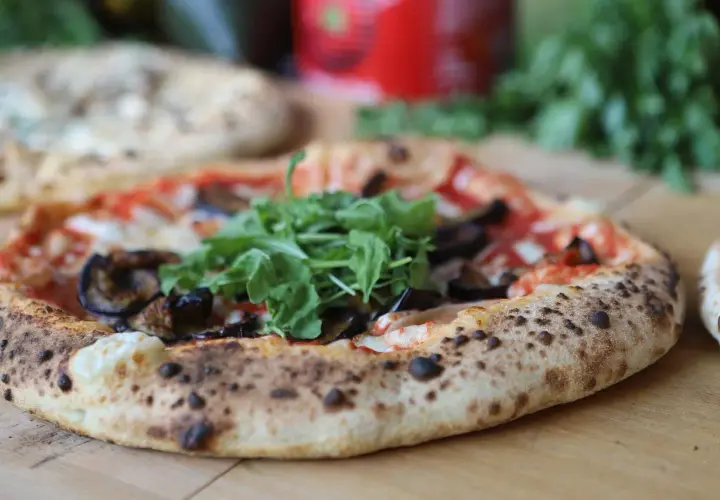 Eine köstliche neapel pizza mit Auberginen und Rucola, frisch aus dem Ofen.