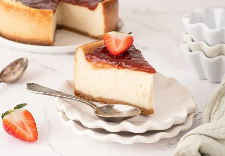 Deliciosa tarta de queso vegana con cobertura de fresa y una fresa fresca encima.