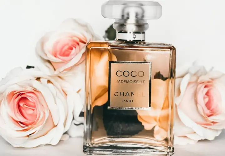 Flakon perfum Chanel Coco Mademoiselle otoczony różowymi różami.