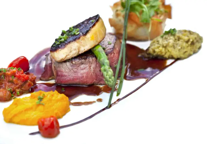 Un steak tendre surmonté de foie gras poêlé, accompagné de purée de patates douces et d'une ratatouille. Un plat qui invite à se demander quoi boire avec du foie gras.