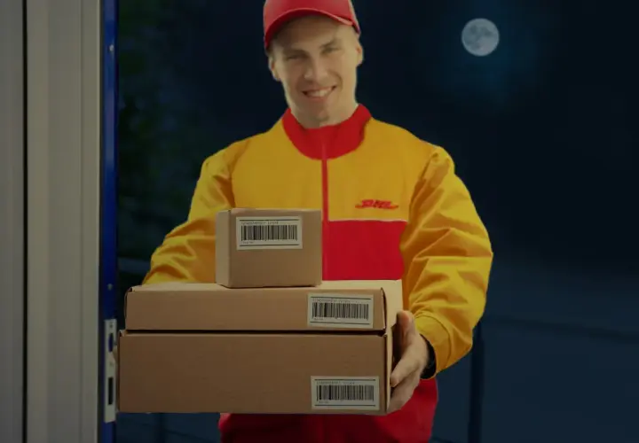 DHL-Bote liefert Pakete bei Nacht aus, der Mond scheint.