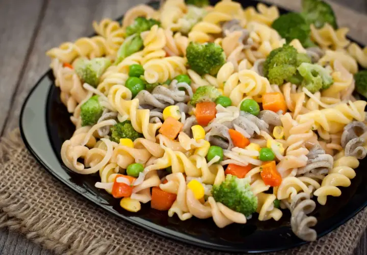 Deliciosa ensalada de pasta vegana con brócoli, guisantes, zanahoria y maíz. Un plato colorido y saludable.