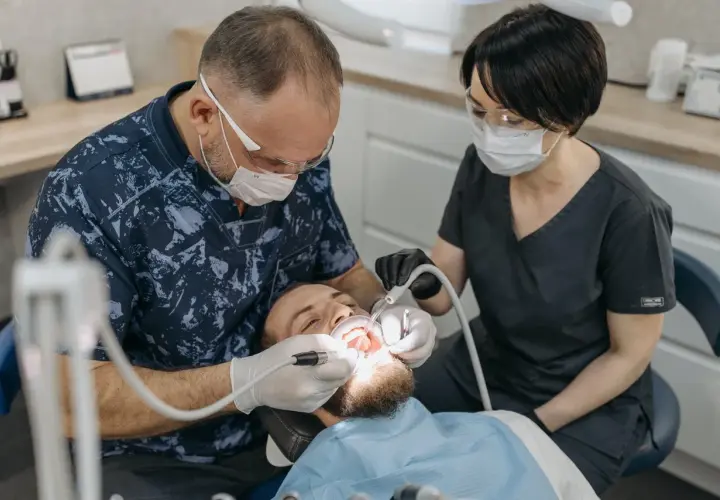 Dentysta odbudowuje ząb jedynkę. Cena zabiegu zależy od metody.