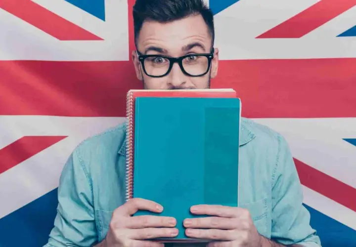 Studente con quaderni davanti al volto, sullo sfondo la Union Jack. Chissà se impara come si dice "venerdì" in inglese.