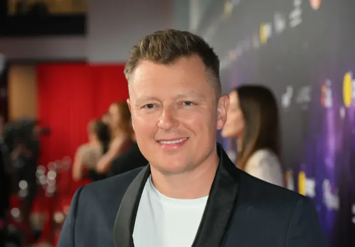 Uśmiechnięty Rafał Brzozowski na ściance. Wiele osób zastanawia się, ile lat ma Rafał Brzozowski, ale na zdjęciu tego nie widać.