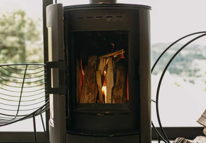 Poêle à bois allumé, avec une prise d'air poele à bois obligatoire pour une combustion optimale. Le feu crépite joyeusement.