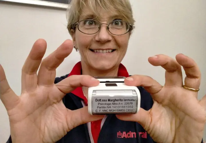 Donna sorridente mostra un timbro con i dati di una psicologa. Utile per sapere cosa scrivere su un timbro psicologo.