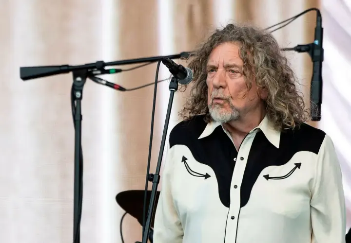 Robert Plant, jeden z legendarnych członków Led Zeppelin, na scenie z charakterystyczną fryzurą i koszulą.