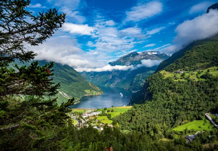 Widok na fiord podczas wycieczki do Norwegii. Statek wycieczkowy wpływa do malowniczej doliny otoczonej zielonymi górami.