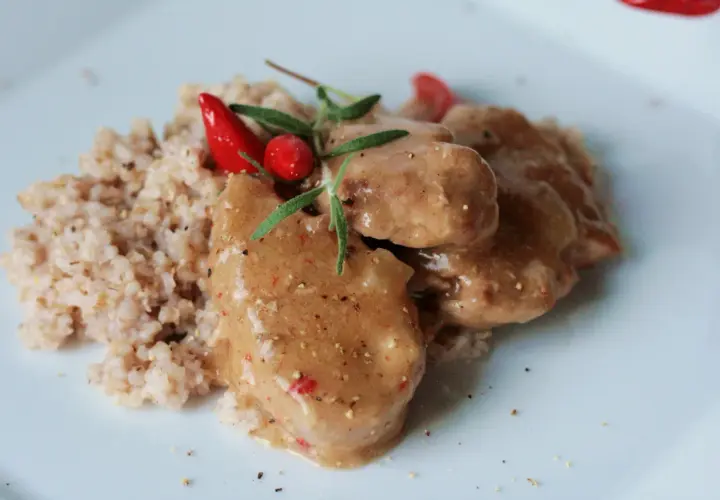 Polędwiczki wieprzowe w sosie własnym, danie Ani gotuje, podane z kaszą i ozdobione papryczką chili i rozmarynem.
