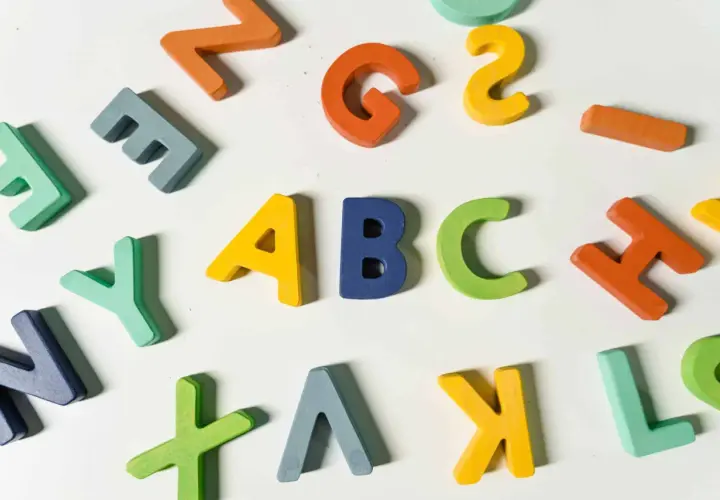 Kolorowe, drewniane litery układają się w napis "ABC", idealne do nauki angielskiego na poziomie a1.