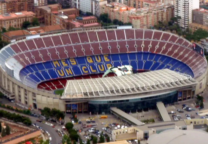 Ogromny stadion Camp Nou w Barcelonie, z napisem "Més que un club" i widoczną pojemnością stadionu.