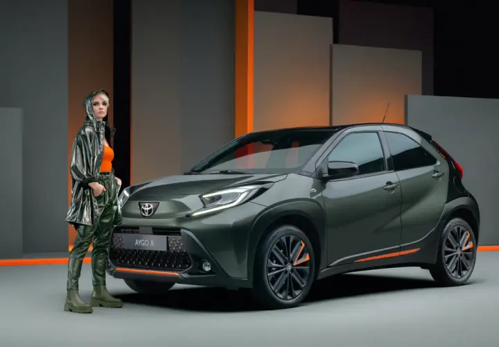 Stylowa kobieta obok zielonego Toyota Aygo X. Wiele osób szuka pozytywnych toyota aygo opinie, ten model wygląda obiecująco.