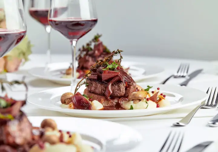 Eleganckie danie z wołowiny z puree, grzybami i cebulą, podane z czerwonym winem. Idealne na specjalne okazje, zastanawiasz się, ile za osobę na wesele?