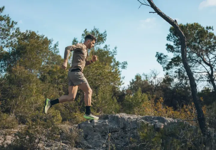 Mężczyzna w sportowym stroju biegnie po kamienistym terenie wśród drzew. To jego trening biegowy metodą Skarżyńskiego.